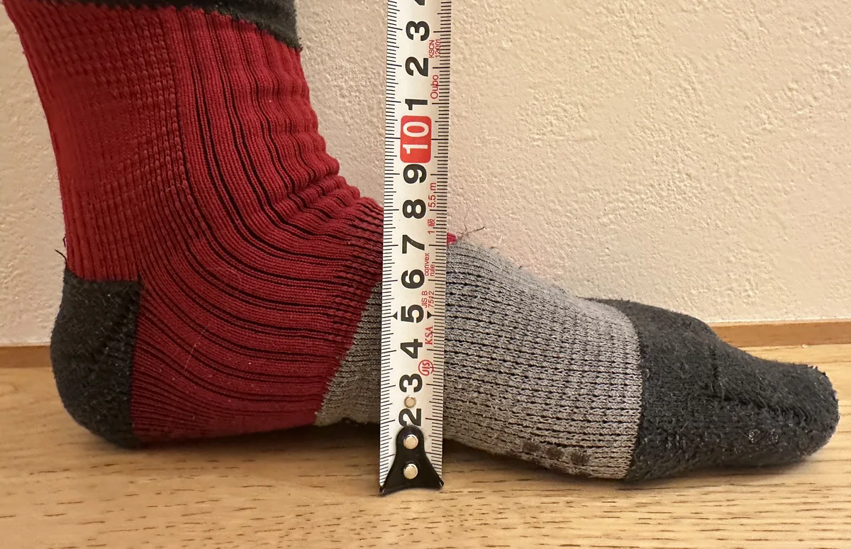 靴下をはいた足の甲の横に、メジャーを縦に立てて甲の高さを測っているところ
