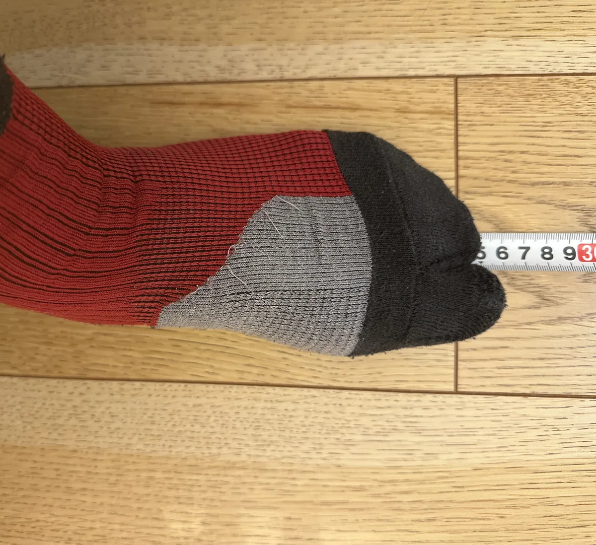 靴下をはいた足のつま先にメジャーを当てて、足の長さを測っているところ