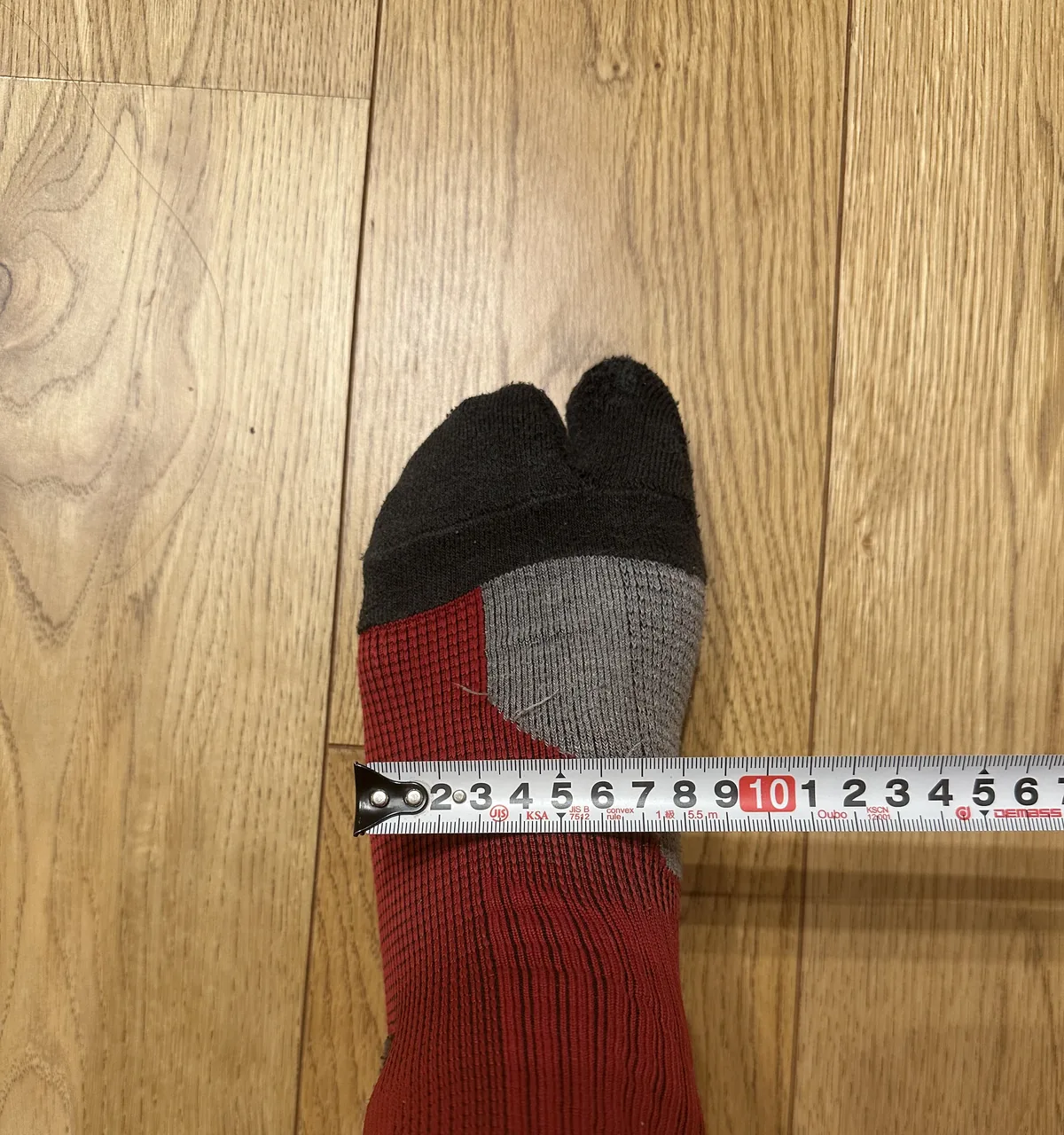 靴下をはいた足の幅がいちばん広いところに、上からメジャーを当てて足幅を測っているところ